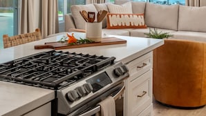 Una cocina moderna con estufa a gas, un comedor con mesa blanca y un sofá con vistas al océano.