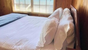 A wooden room with a bed, a window with blinds, and a view of the sky. - Oceanfront Cabin (Fresh Creek)