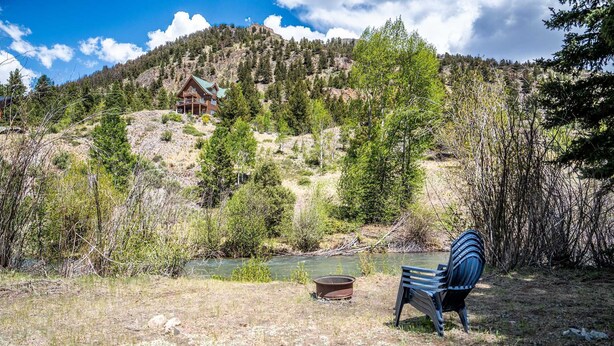 A cabin with a view of a mountain and a river.