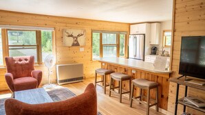 A cozy cabin interior with a wooden interior, a bar area, and a large TV.