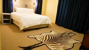Ein Schlafzimmer mit einem Bett, einem Nachttisch und einem Zebra-Teppich.