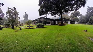 A well-maintained lawn with a stone building, surrounded by trees and a small garden area.