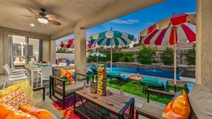 Eine Terrassenfläche mit Sitzgelegenheiten, einem Pool und bunten Sonnenschirmen.