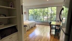 Una camera compatta con un letto, una scrivania piccola e una finestra.