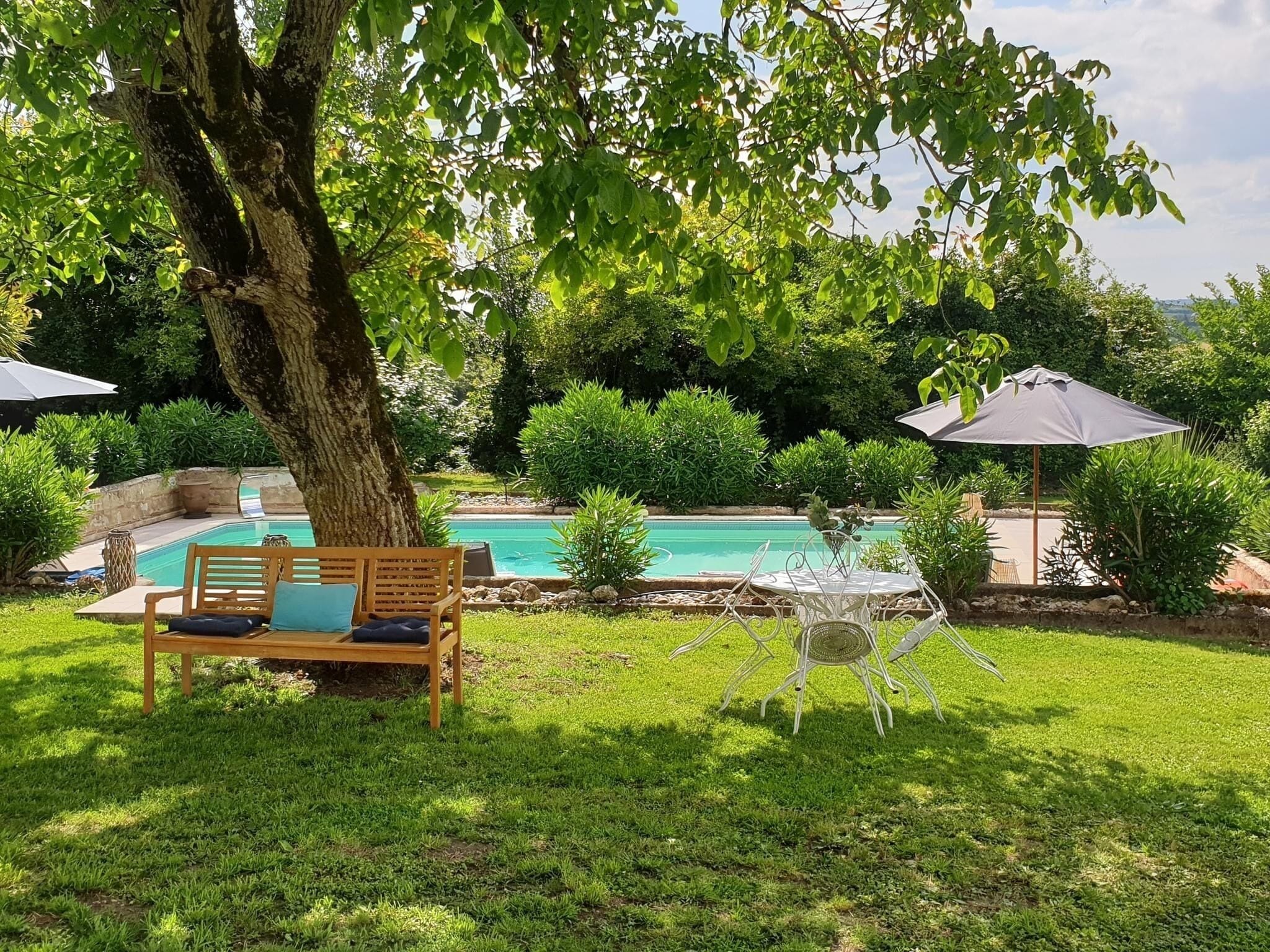 A backyard with a swimming pool, a wooden bench, and a white chair.