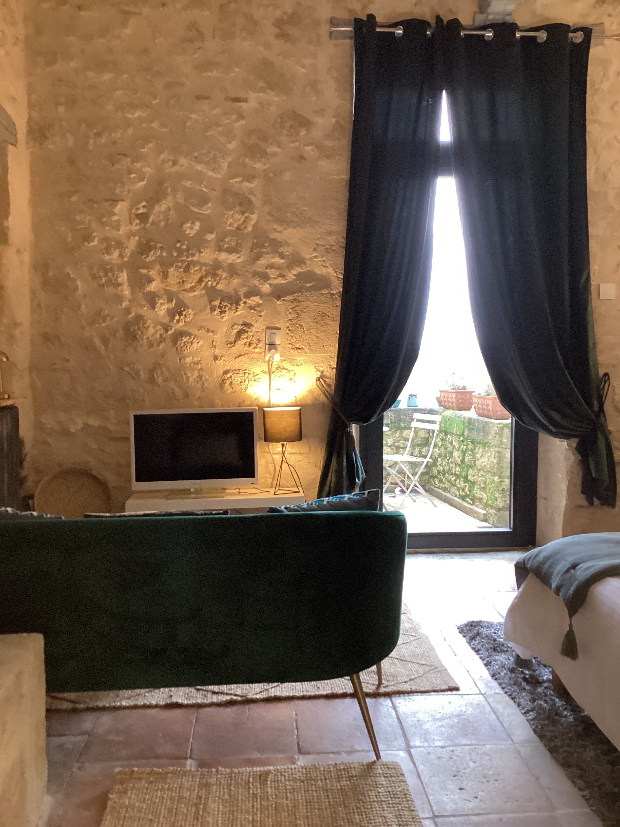 Ein Zimmer mit Steinsandsteinwand, Fernseher, Lampe und Blick ins Freie.