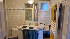 A bathroom with a toilet, sink, mirror, and towel rack.