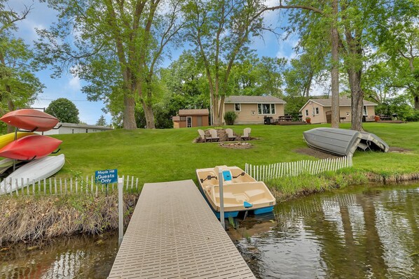 Ein Steg am See mit einem Boot, einem Schild mit der Aufschrift 'Nur für Gäste von Maple Hill' und einem Haus im Hintergrund.