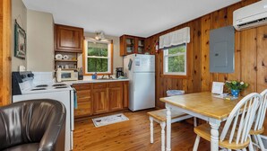 Una cocina compacta con armarios de madera, un refrigerador, una estufa y una mesa de comedor con sillas.