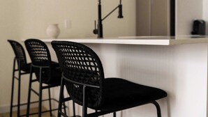 A kitchen area with a white countertop, black chairs with woven backs, and a black faucet. - Maison Place Jacques-Cartier • Luxury Loft • Old Montreal • Self Check-In Access • Full Kitchen • Wi-Fi • AC (Montréal)