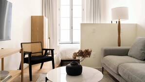 A modern, well-lit room with a bed, a sofa, a dining table, and a chair. There is a vase with dried flowers on the table. - Maison Place Jacques-Cartier • Luxury Loft • Old Montreal • Self Check-In Access • Full Kitchen • Wi-Fi • AC (Montréal)