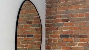 A room with a brick wall, a black oval mirror, and a black bench. - Maison Place Jacques-Cartier • Luxury Loft • Old Montreal • Pet Friendly • Full Kitchen • Wi-Fi • AC (Montréal)