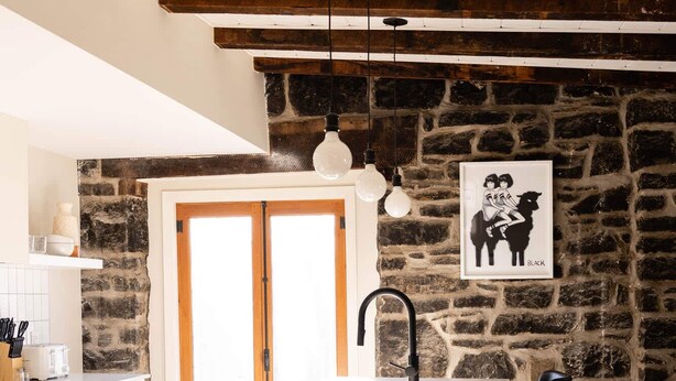 Una cocina con una isla central, una pared de piedra y una obra de arte blanco y negro.