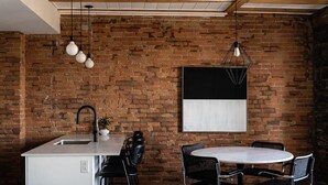 A kitchen with a brick wall, a sink, and a round dining table with chairs. - Maison Place Royale • Luxury Waterfront One-Bedroom Apartment • Old Montreal • Water View St. Lawrence River • Full Kitchen • Stone Walls • Wi-Fi • AC (Montréal)