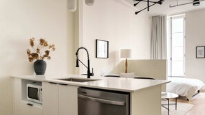 A modern kitchen with a built-in microwave, dishwasher, and a vase with dried flowers.