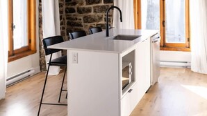Una cocina moderna con pared de piedra, vigas de madera y una isla grande.