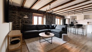 A modern living room with a sectional sofa, a coffee table, and a kitchen area with bar stools. - Maison Place Royale • Luxury Two-Bedrooms Apartment • Old Montreal • Full Kitchen • Stone Walls • Wi-Fi • AC (Montréal)