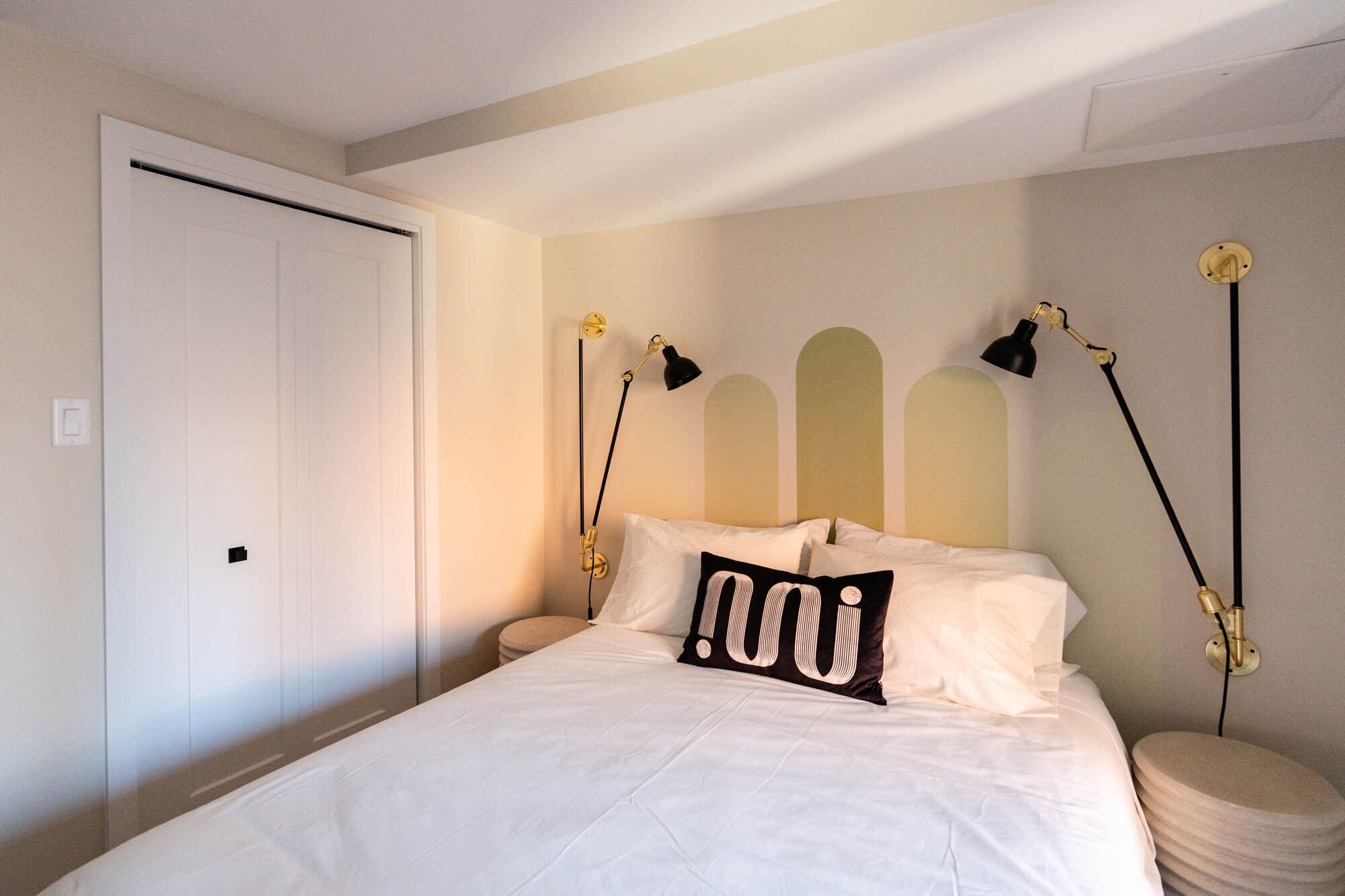 Una camera da letto con un letto, comodini, lampade e una porta.