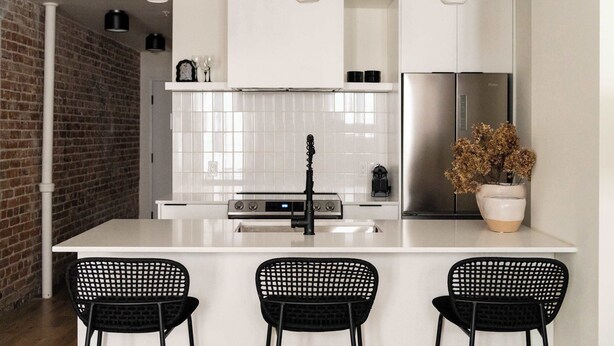 A modern kitchen with a central island, three black chairs, and a potted plant. - Maison Place Jacques-Cartier • Luxury Loft • Old Montreal • Central • Full Kitchen • Wi-Fi • AC (Montréal)