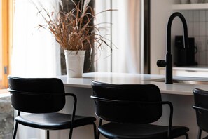 A kitchen with a white countertop, black chairs, and a potted plant. - Maison Place Royale • Luxury Two-Bedrooms Apartment • Old Montreal • Full Kitchen • Stone Walls • Wi-Fi • AC (Montréal)