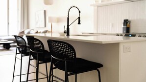 Una cucina moderna con isola bianca, sgabelli neri e una lampada a sospensione.