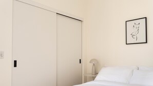 Camera d'albergo con un letto, un comodino con una lampada, un'opera d'arte incorniciata e un armadio.