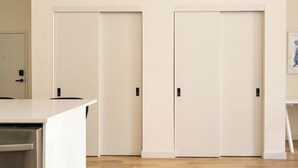 Una stanza con una scrivania bianca, due porte bianche e un quadro appeso al muro.