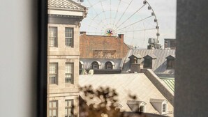 A view of a Ferris wheel through a window, with a vase of dried flowers on a windowsill.