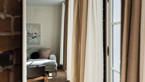 Ein schmaler Flur mit einem Bett, einem Fenster und Vorhängen.