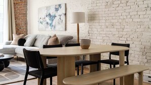 Ein Essbereich mit rundem Tisch, vier Stühlen, einer Bank und einer Lampe.