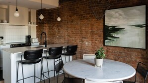 Una cucina moderna con parete in mattoni, un tavolo da pranzo rotondo con sedie e un lampadario a sospensione.