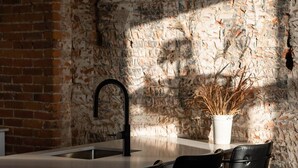 A kitchen with a brick wall, a modern faucet, and three pendant lights.