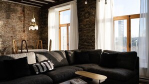 A modern living room with a dark gray sectional sofa, a round coffee table, and a chandelier.