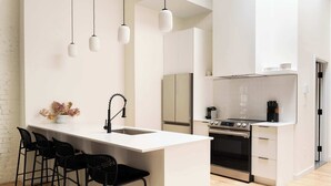 A modern kitchen with a central island, black bar stools, a stainless steel oven, and hanging pendant lights. - Maison Place Jacques-Cartier • Luxury One-Bedroom Apartment • Old Montreal • Freestanding bath • Full Kitchen • Skylight • Wi-Fi • AC (Montréal)