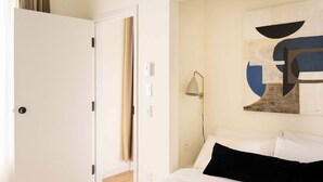 A hotel room with a bed, a painting on the wall, and a door. - Maison Place Jacques-Cartier • Luxury One-Bedroom Apartment • Old Montreal • Freestanding bath • Full Kitchen • Skylight • Wi-Fi • AC (Montréal)