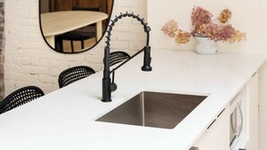 A kitchen with a white countertop, black faucet, and hanging pendant lights. - Maison Place Jacques-Cartier • Luxury One-Bedroom Apartment • Old Montreal • Freestanding bath • Full Kitchen • Skylight • Wi-Fi • AC (Montréal)