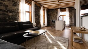 A cozy living room with a sofa, a small table, and a kitchen area with a sink and bar stools. - Maison Place Royale • Luxury Waterfront Two-Bedrooms Apartment • Old Montreal • Water View St. Lawrence River • Full Kitchen • Stone Walls • Wi-Fi • AC (Montréal)