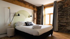 A bedroom with a bed, a lamp, and a window with curtains. - Maison Place Royale • Luxury Waterfront Two-Bedrooms Apartment • Old Montreal • Water View St. Lawrence River • Full Kitchen • Stone Walls • Wi-Fi • AC (Montréal)