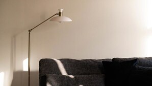 A modern room with a grey sofa, a floor lamp, and a plain wall. - Maison Place Royale • Luxury Waterfront Two-Bedrooms Apartment • Old Montreal • Water View St. Lawrence River • Full Kitchen • Stone Walls • Wi-Fi • AC (Montréal)