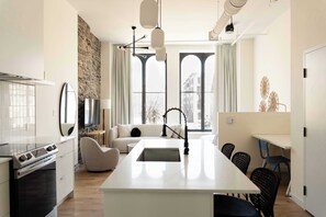 Una cocina moderna con una isla central, un comedor con sillas y ventanas amplias con vista a la ciudad.