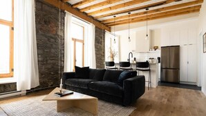 Una sala de estar moderna con un sofá negro, una mesa de centro de madera y una pared de piedra.