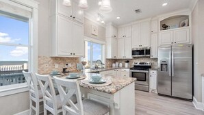 A kitchen with white cabinetry, a granite countertop, and a view of the ocean. - Beachfront | Hot Tub | Tiki Bar | Fenced Yard (Crystal Beach)