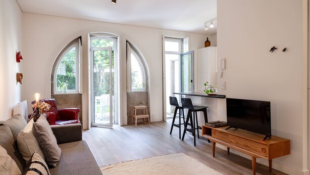 Una sala de estar moderna con un sofá, un televisor y una zona de comedor con sillas.