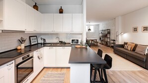 Una cocina moderna con armarios blancos, una isla central y una zona de comedor con sofá y sillas.