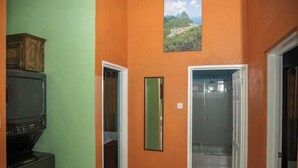 A hallway with an orange wall, a green door, and a framed picture of a landscape. - Lovely entire new 2 Bedroom Apartment in Corinth (Gros Islet Castries)