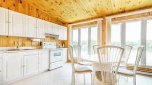 A kitchen with white cabinets, a stove, and a dining area with white chairs. - Jack's Lake Retreat - Perfect for multi-families! (Golden Valley)
