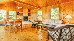 A wooden cabin interior with a dining area, sofa, and a fireplace. - Jack's Lake Retreat - Perfect for multi-families! (Golden Valley)