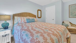 A bedroom with a bed, a nightstand, a wicker chair, a door, and a wall-mounted mirror. - Forest Landing Bethany Beach Pool, Kids Mega Room (Frankford)