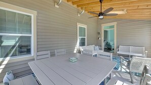A covered outdoor area with a table and chairs, a ceiling fan, and a view of the house through an open door. - Forest Landing Bethany Beach Pool, Kids Mega Room (Frankford)