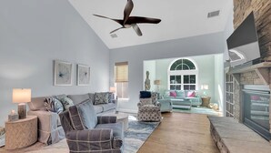 A modern living room with a fireplace, a ceiling fan, and a view to a dining area. - Forest Landing Bethany Beach Pool, Kids Mega Room (Frankford)